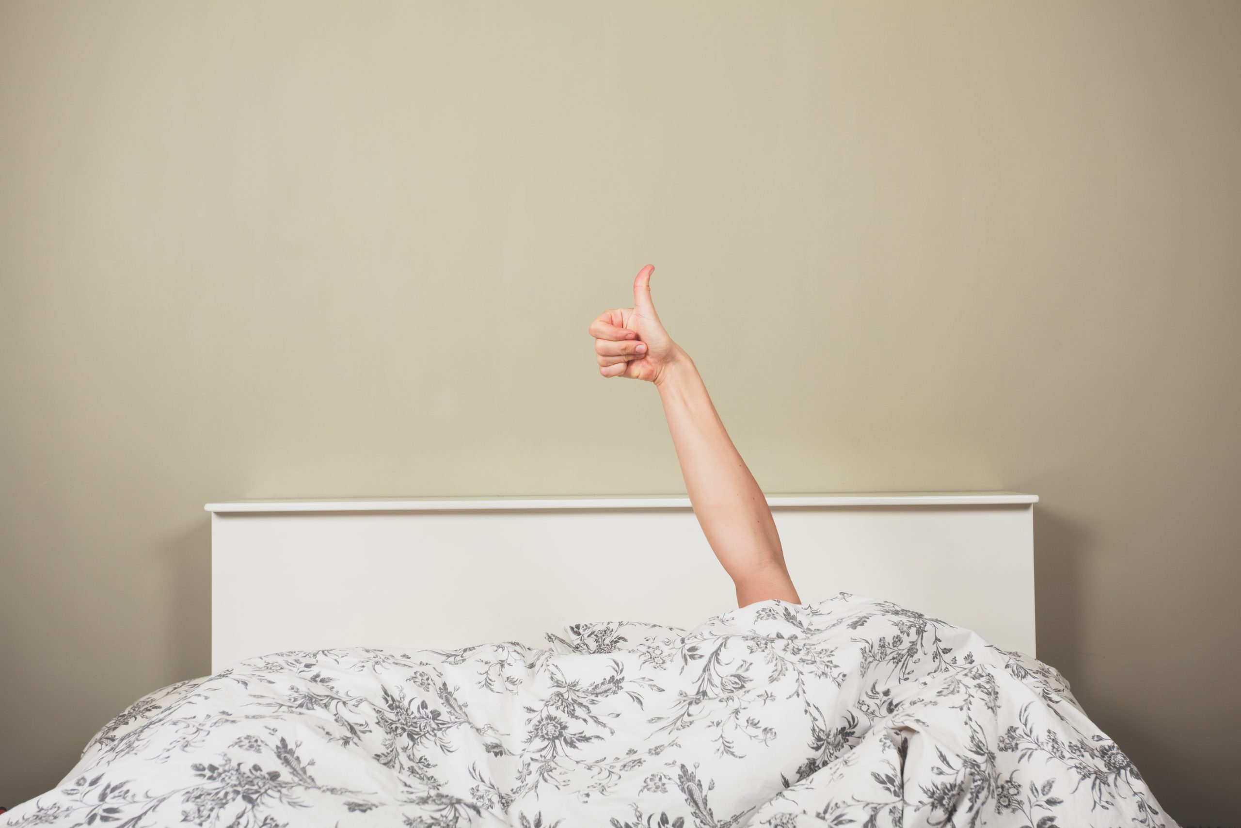 Woman in bed giving thumbs up