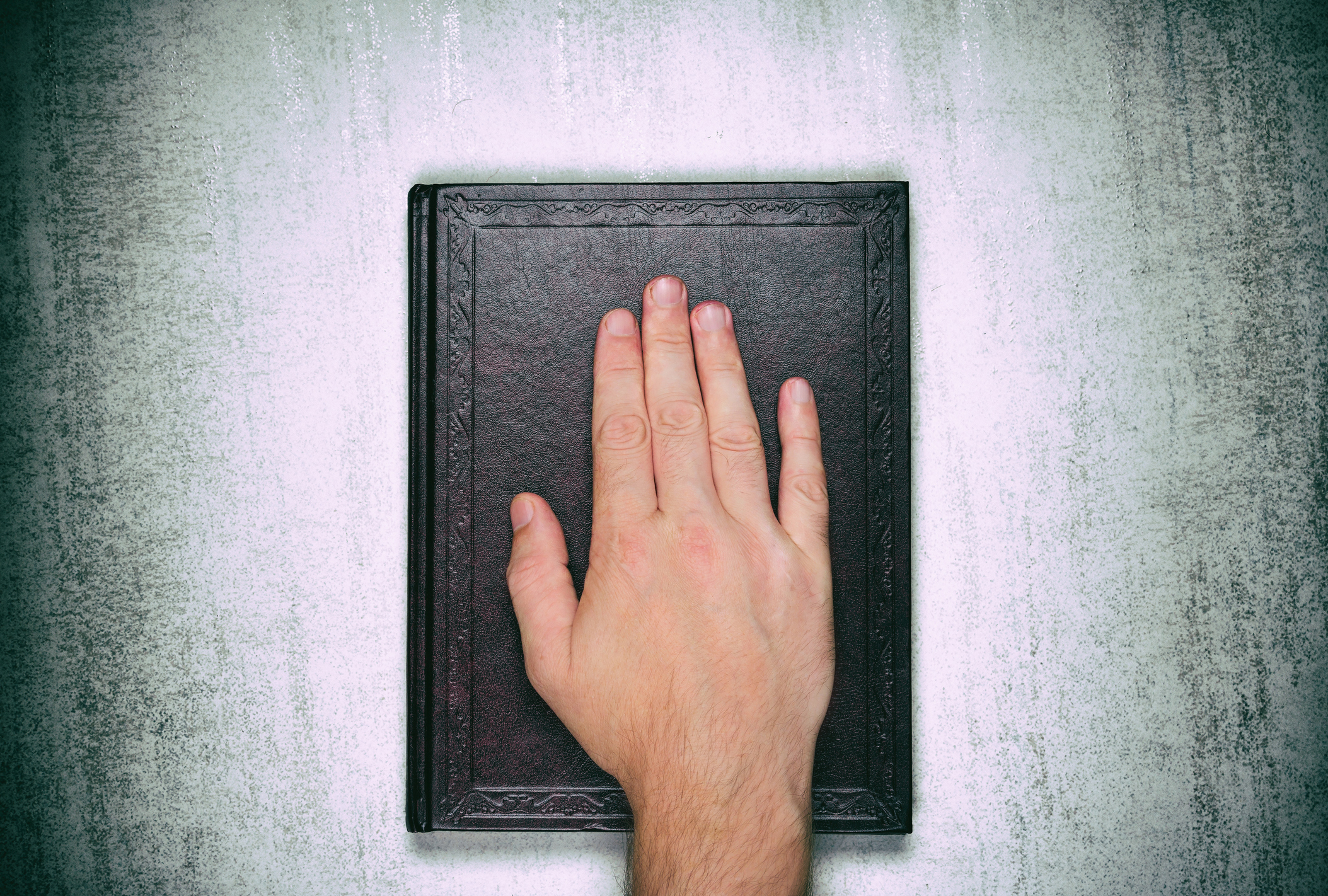A male palm on a book, an oath on the bible, Top view close up