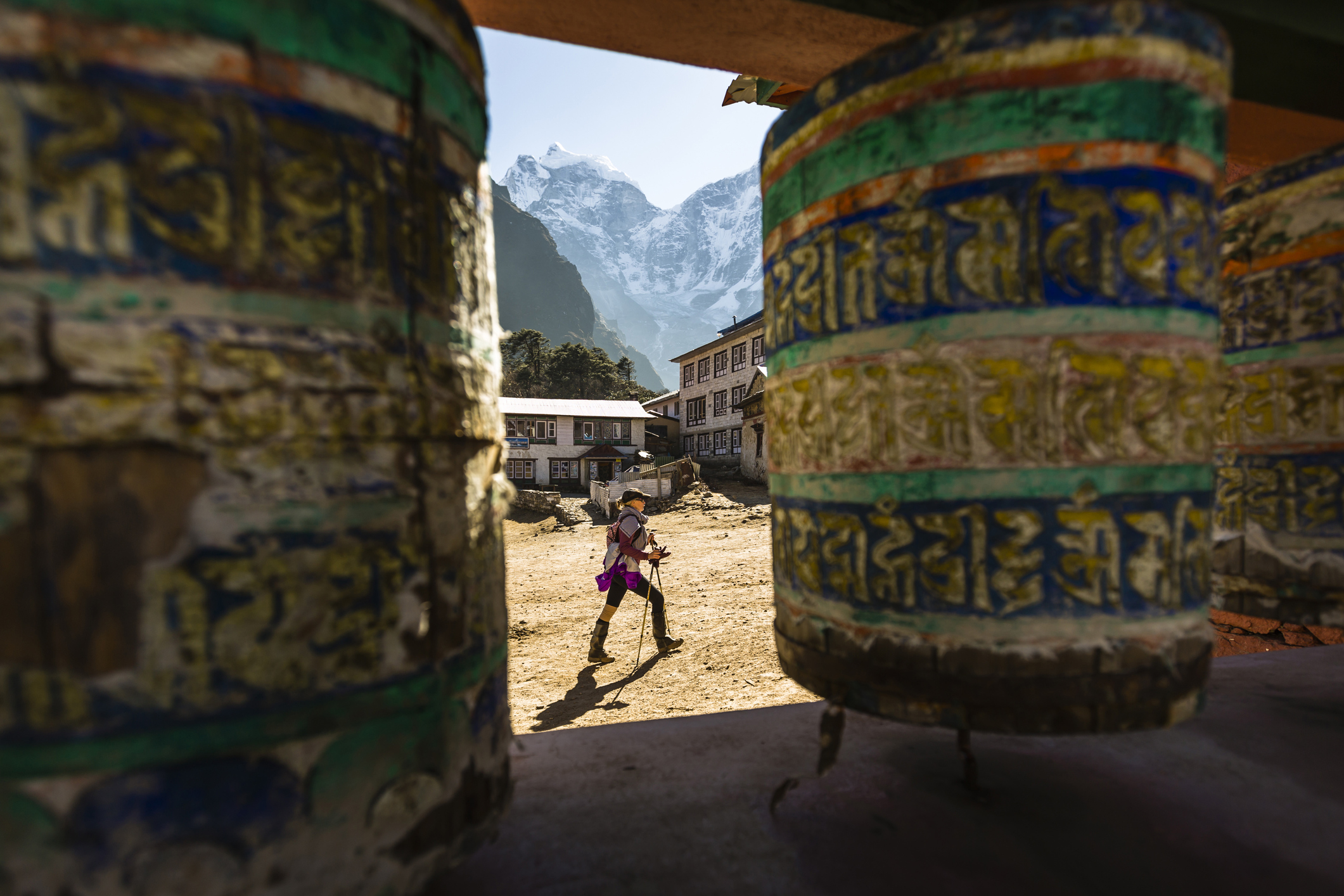 A woman is hiking past prayer wheels at Tengboche Monastery, Nepal.