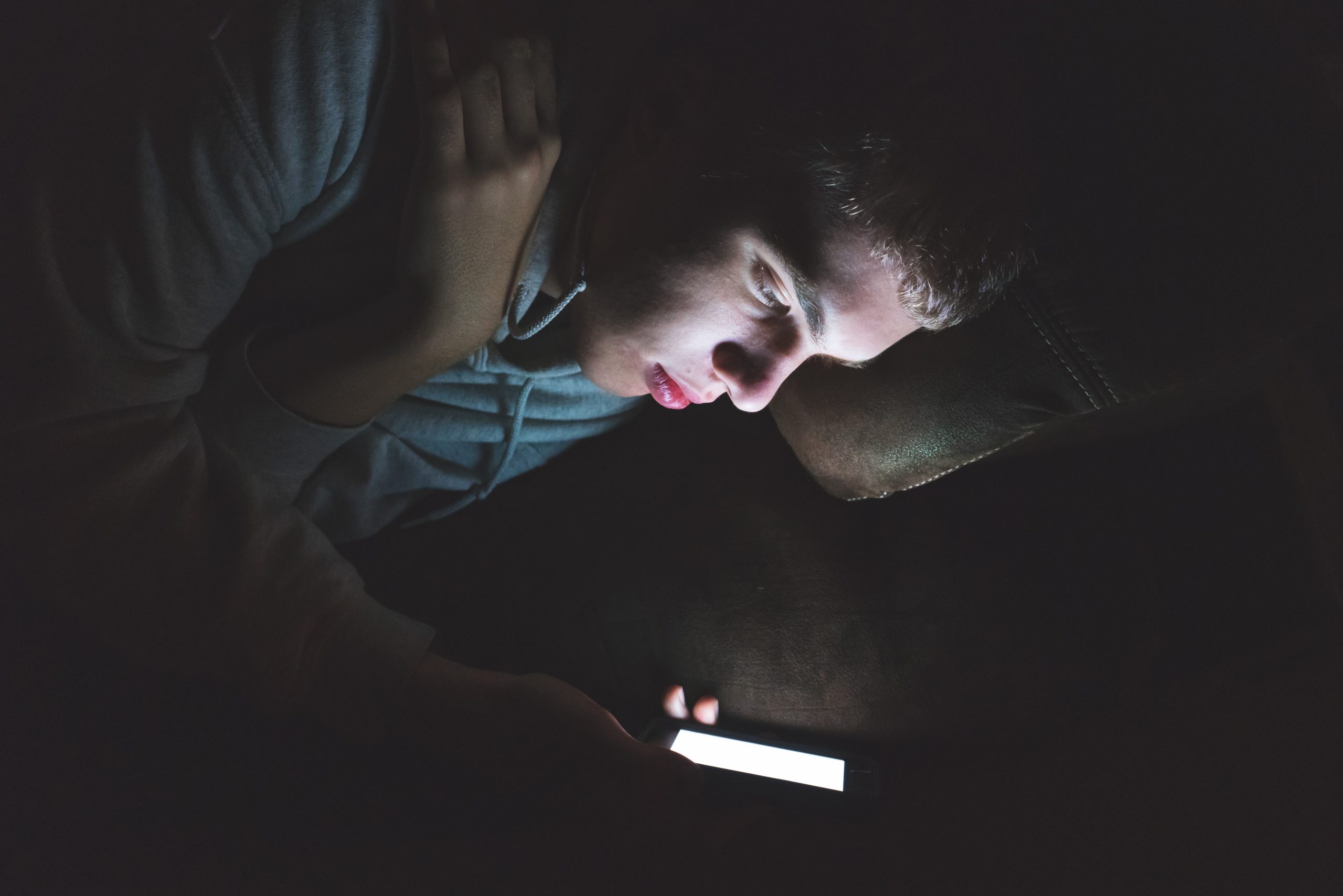 Teenager on his smartphone in the dark.