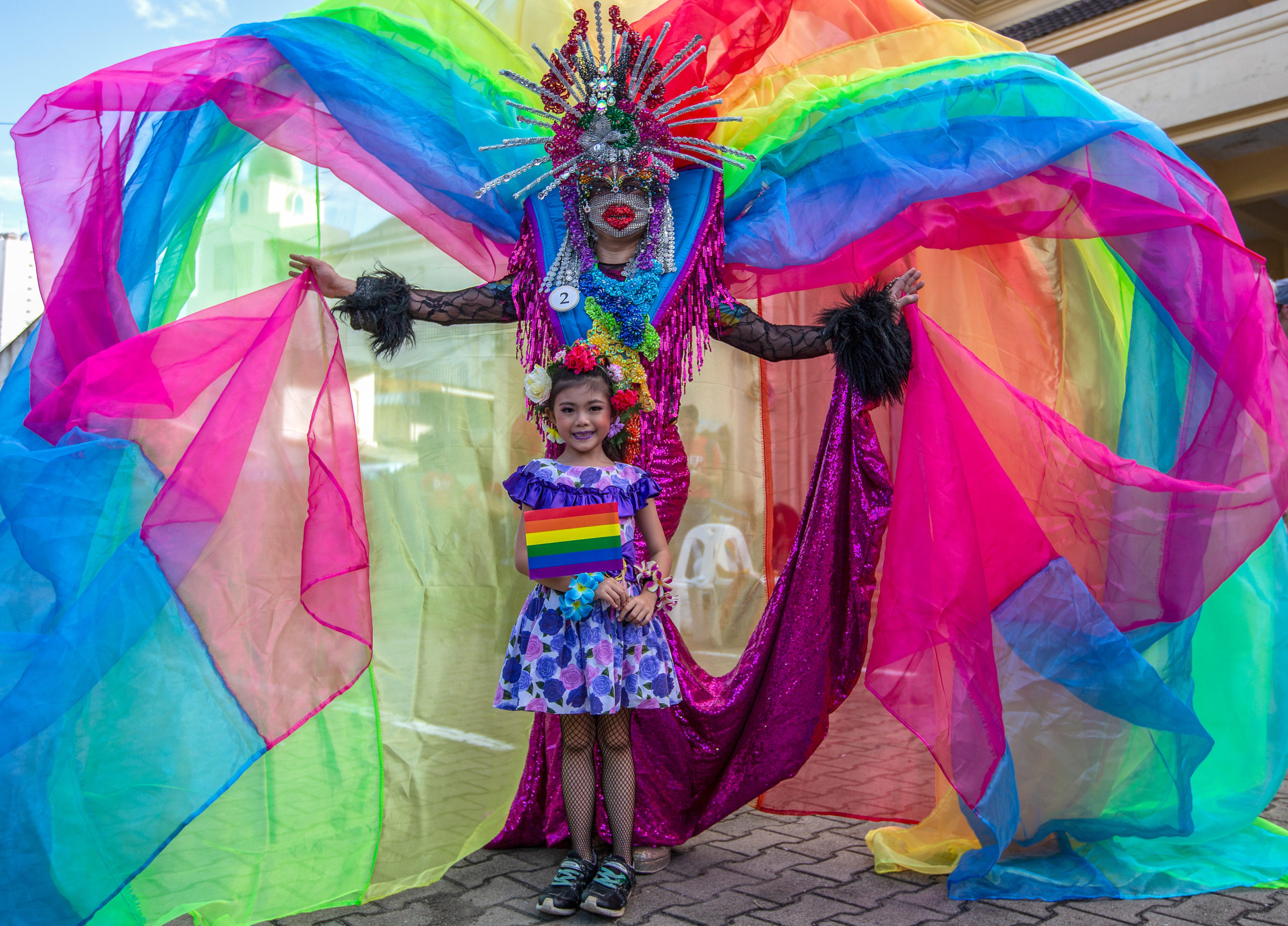 An activist in a rainbow costume and a kid are posing for