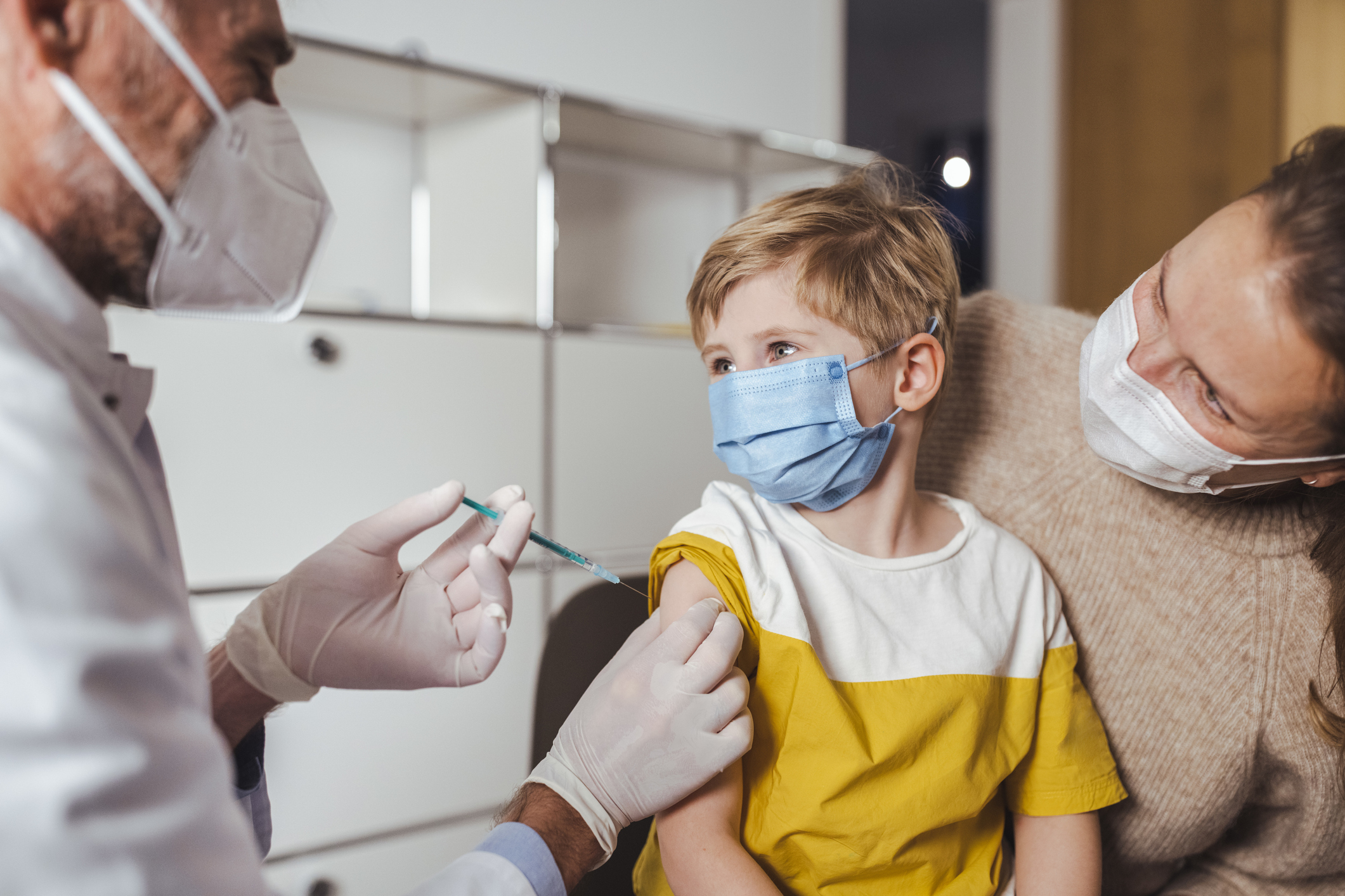 Boy looking at doctor holding vaccine injection in center
