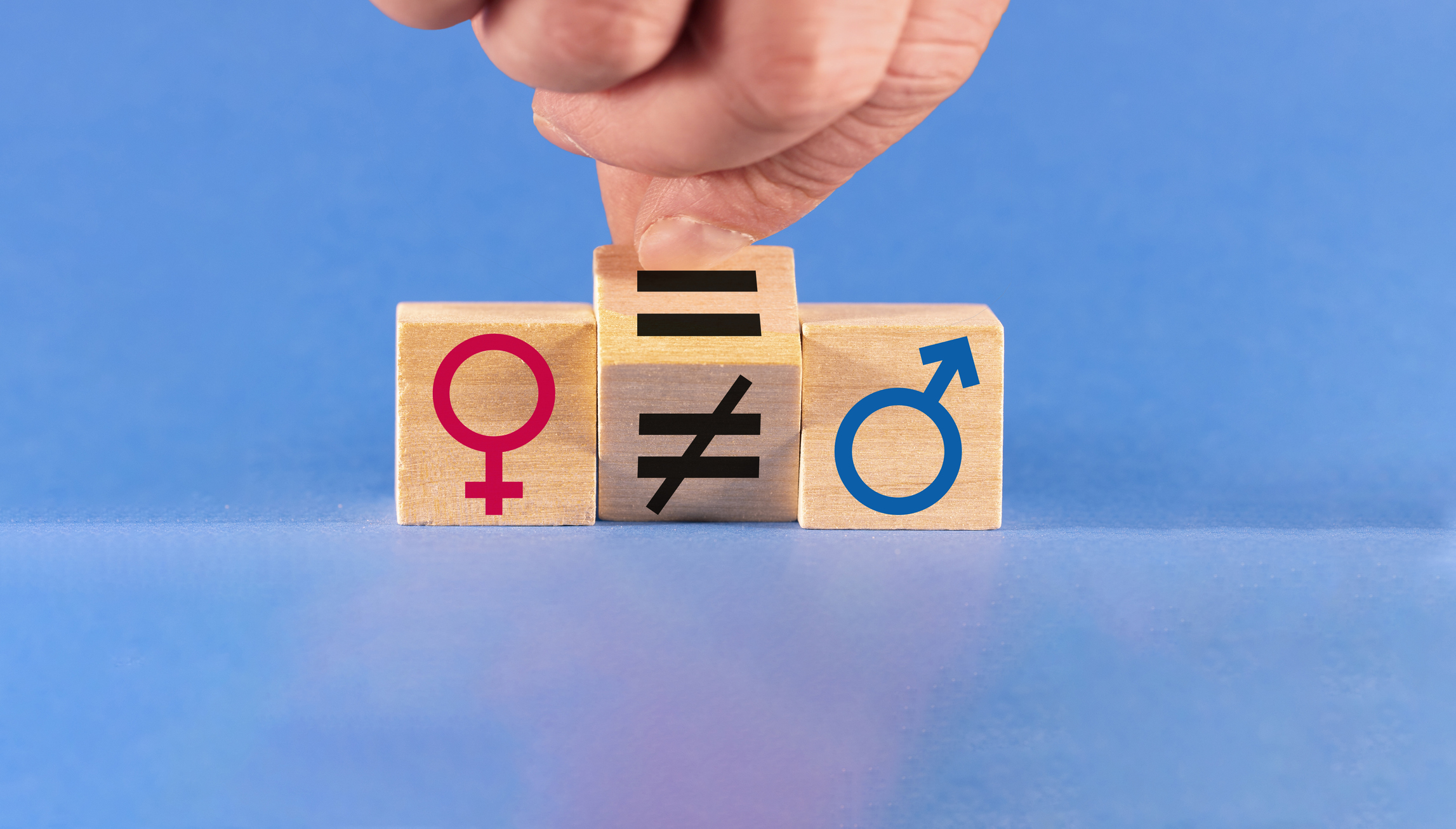 Concept of gender equality. A hand changes an unequal sign to an equal sign between male and female symbols.