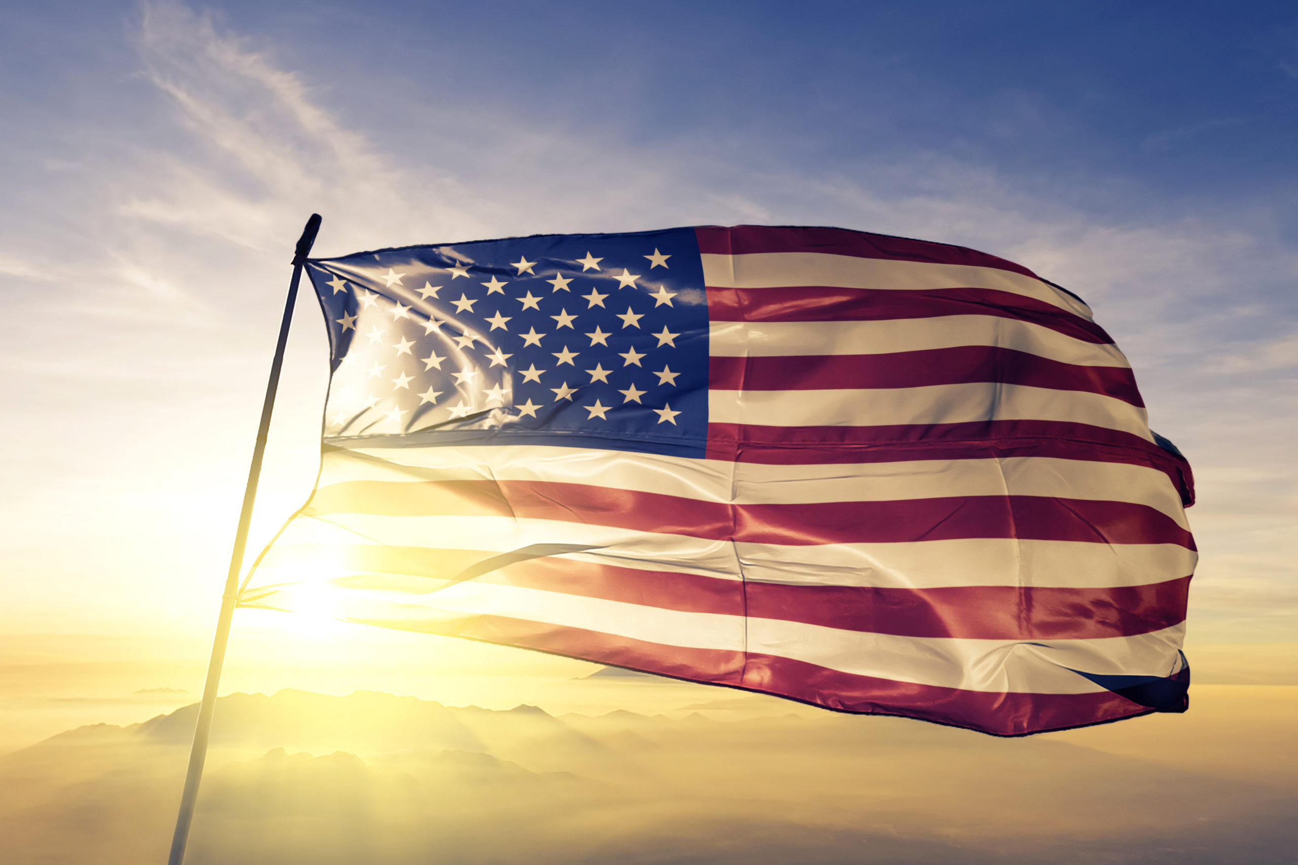 United States american usa us flag textile cloth fabric waving on the top sunrise mist fog