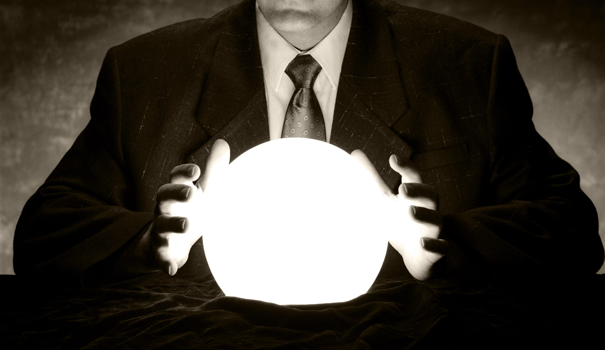 Man in suit holds hands over glowing crystal ball