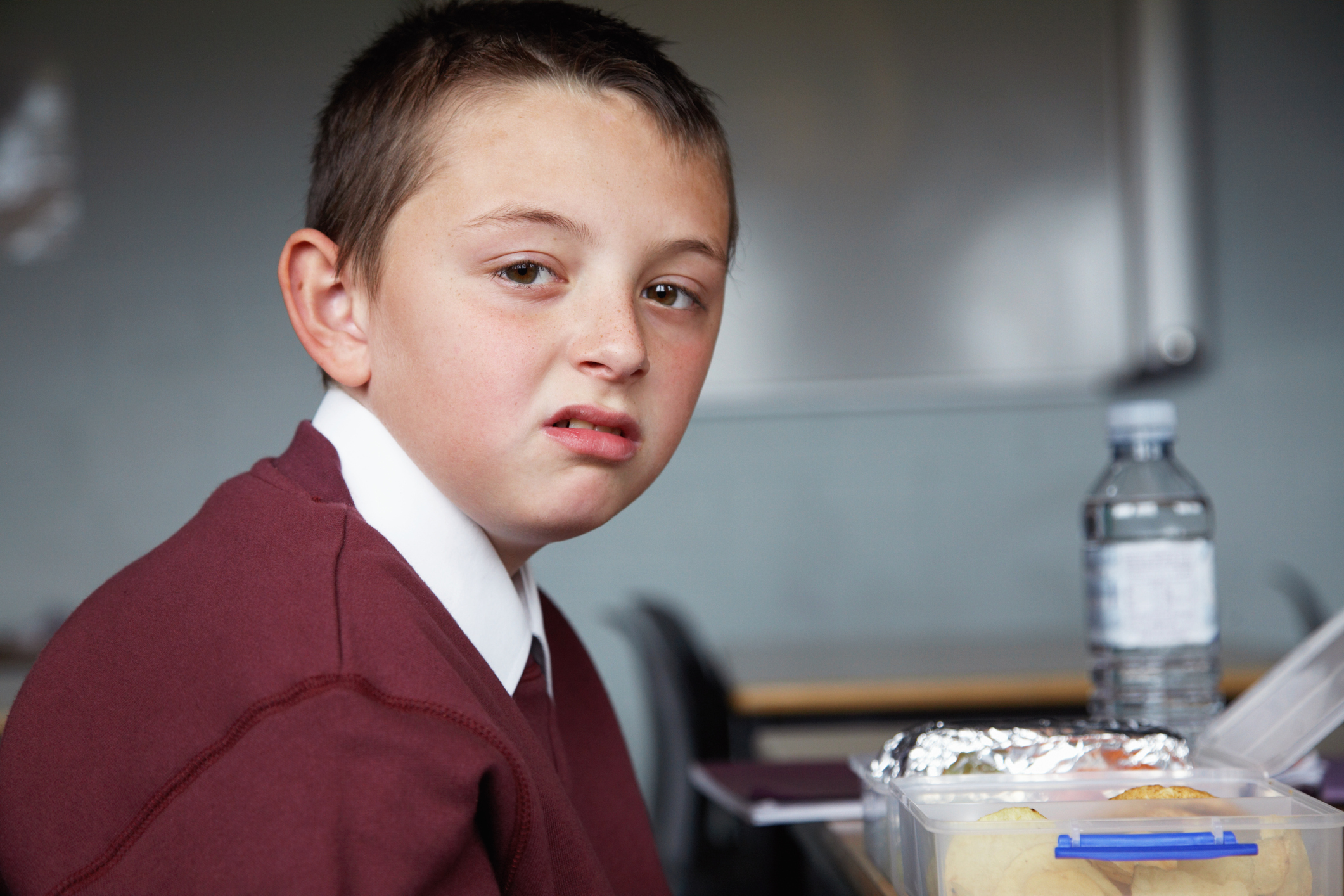 Schoolboy (8-10) desk, packed lunch on table, portrait