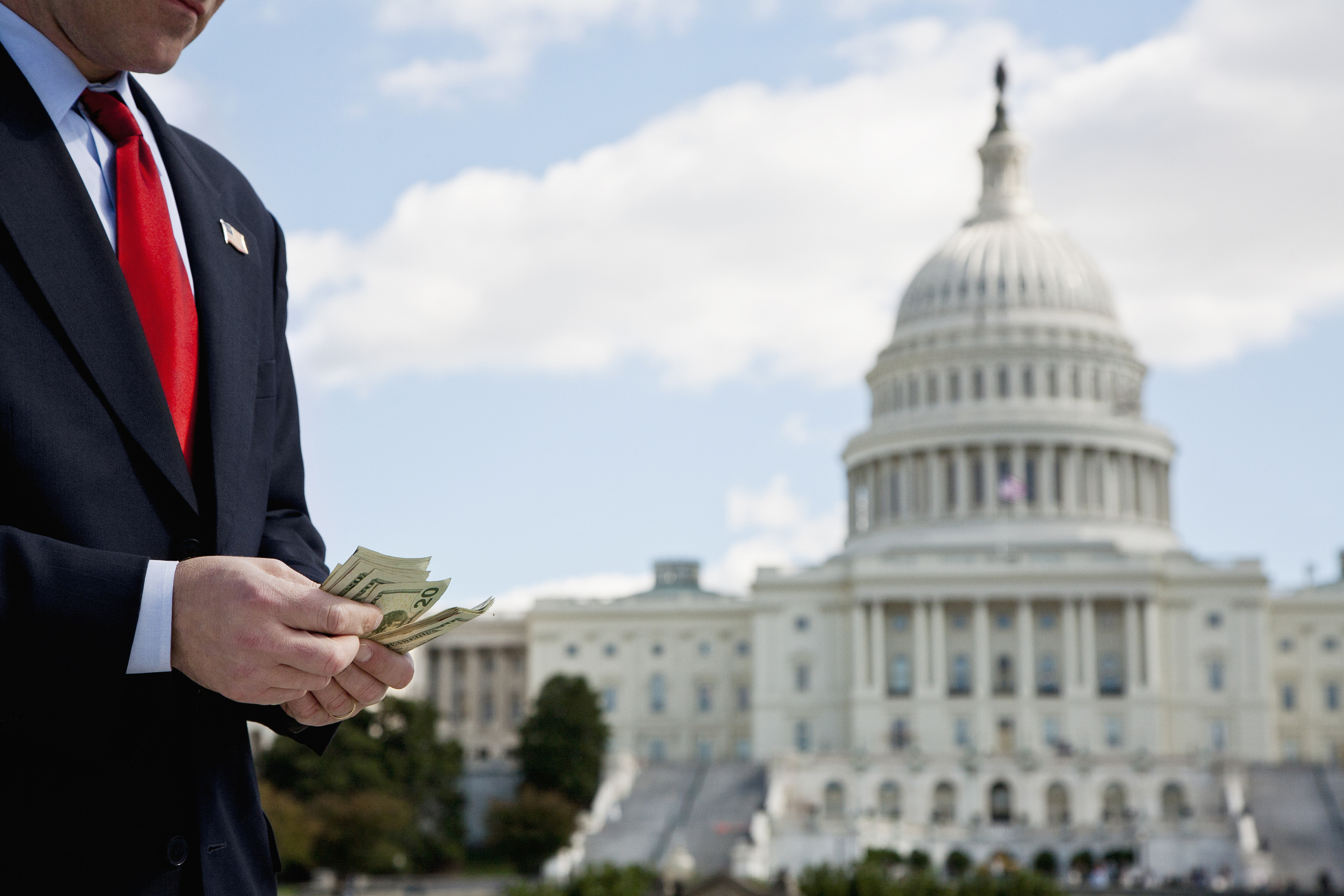 A politician counting money in front of the US Capitol Building