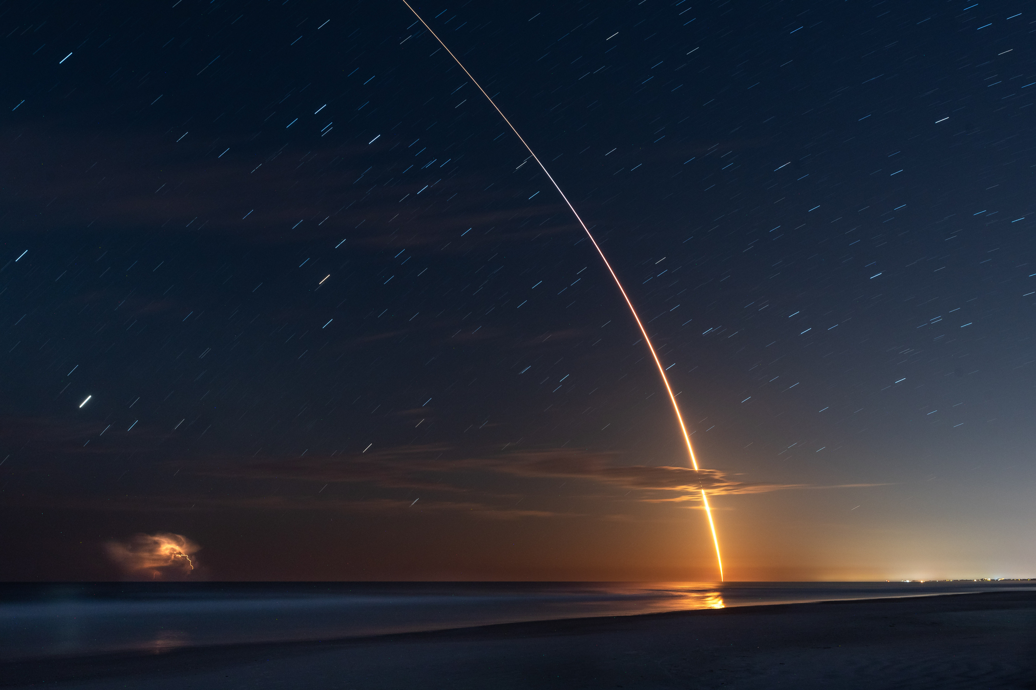 SpaceX Falcon 9 rocket launch light trail in sky at night, St Augustine Beach, Florida, USA