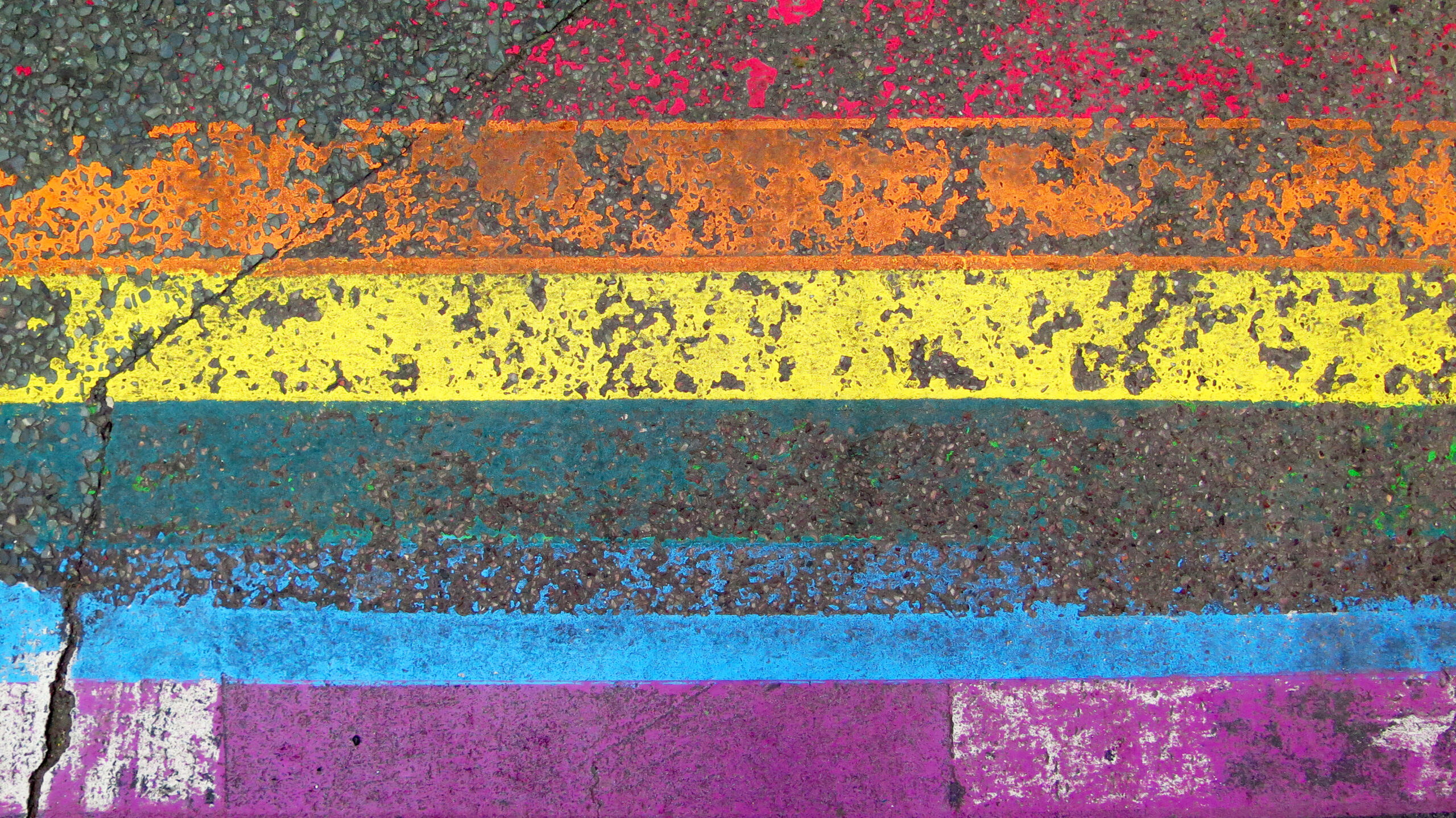 LGBT+ flag painted, weathered and cracked on a street in Paris