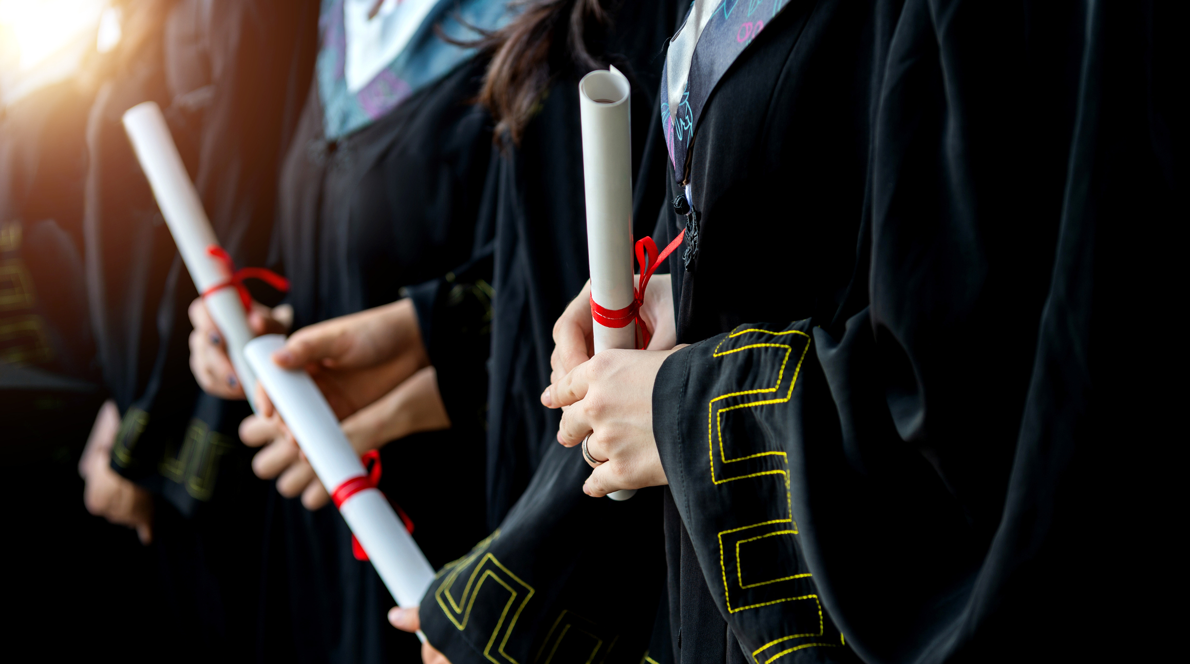 Graduated students holding diplomas in a line