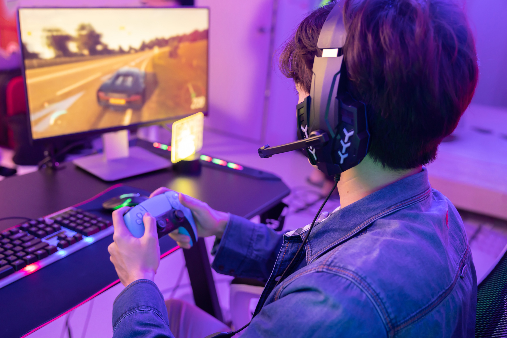 Gamer Playing  Driving Game with Game Controller in Neon Game Room