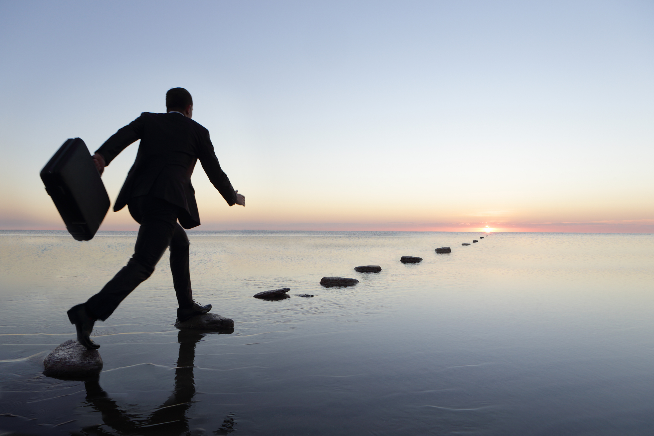 man at sunset in suit , running over steppingstone