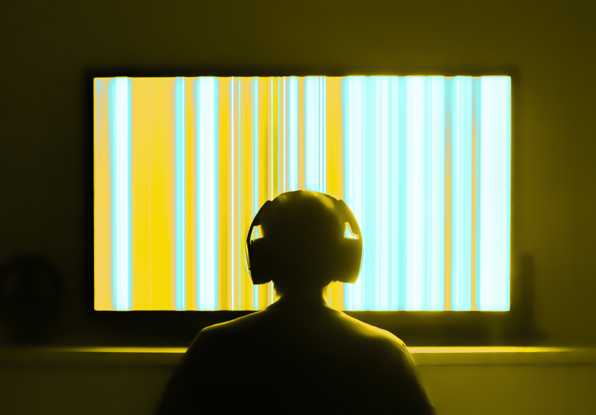 Silhouetted person with headphones watching large tv screen