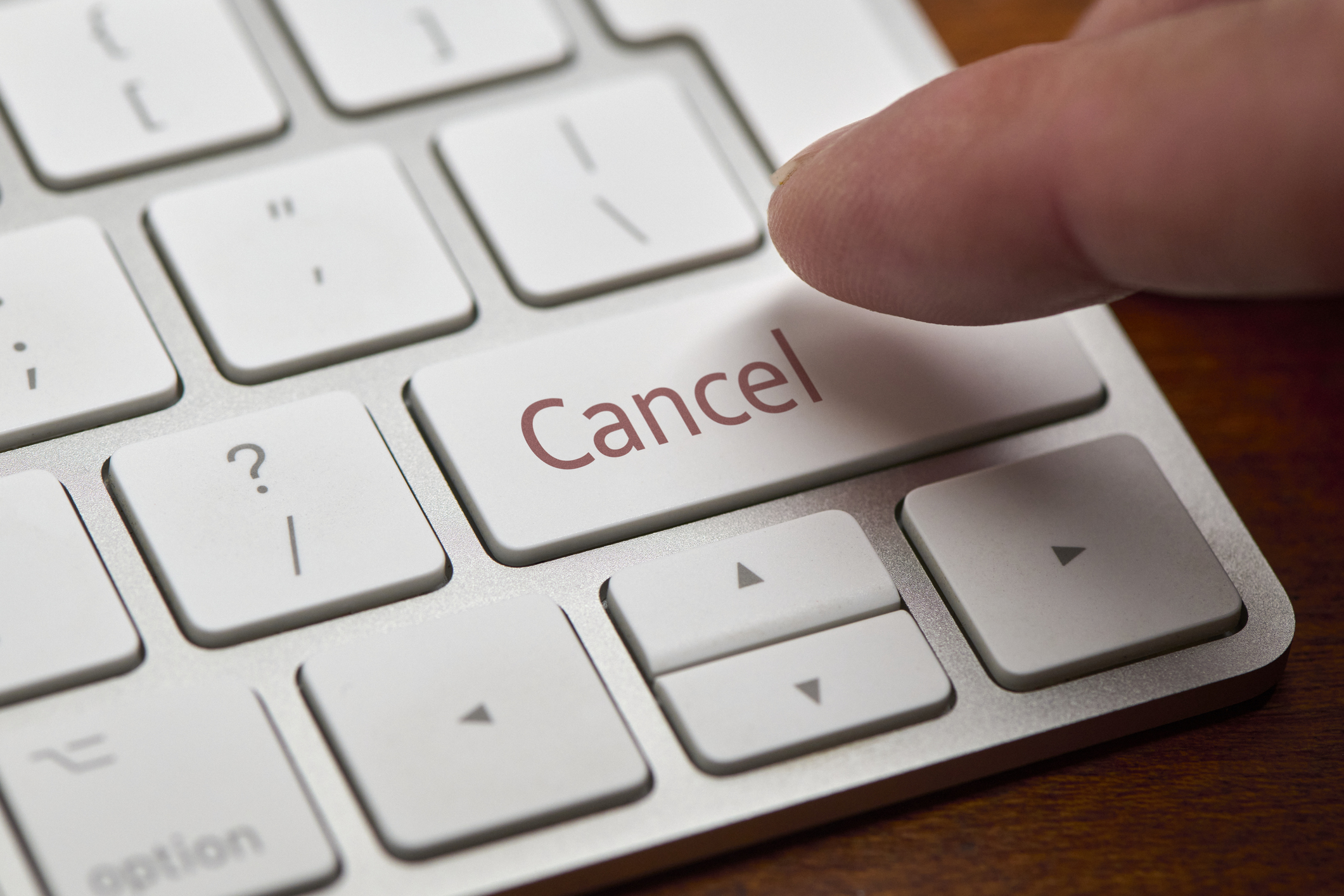 A finger about to press a “Cancel” button on a computer keyboard.