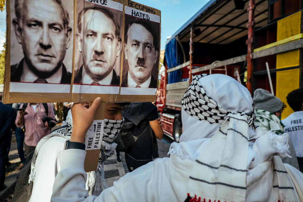 A protester holds a placard comparing Netanyahu to Hitler