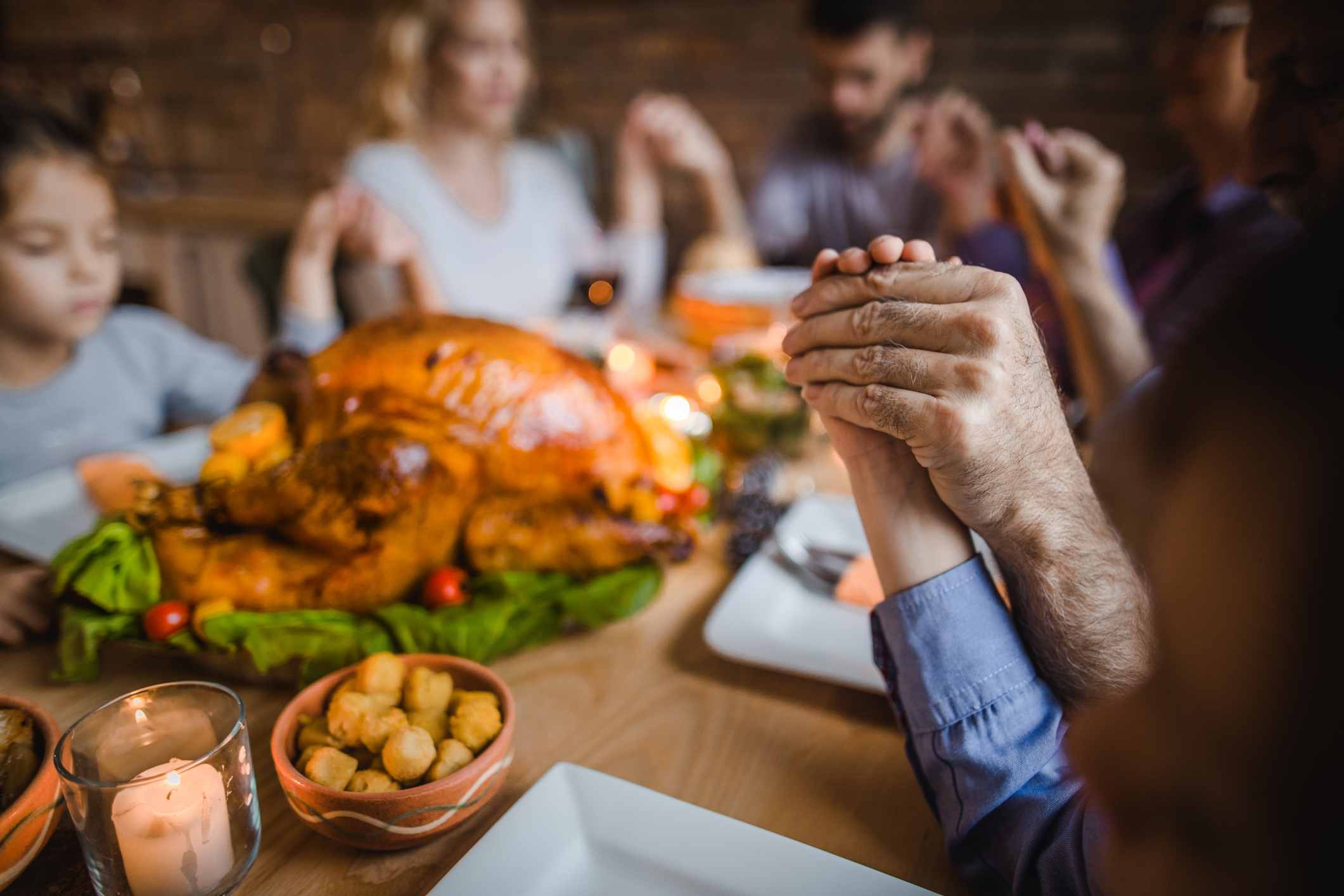 Close up of human hands during a pray on Thanksgiving dinner.