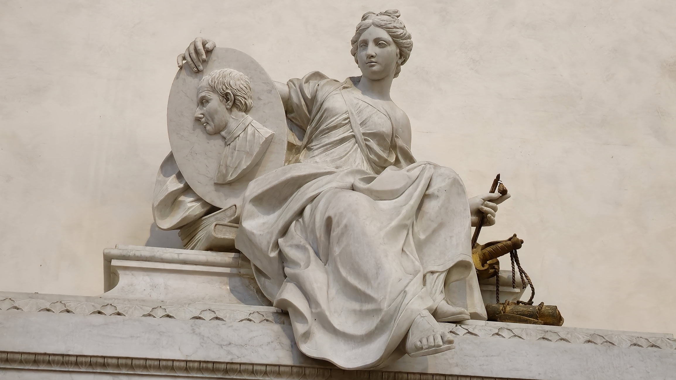 Machiavelli’s tomb in Santa Croce shows a female figure holding his portrait medallion and a set of books and a sword symbolizing knowledge and political power.