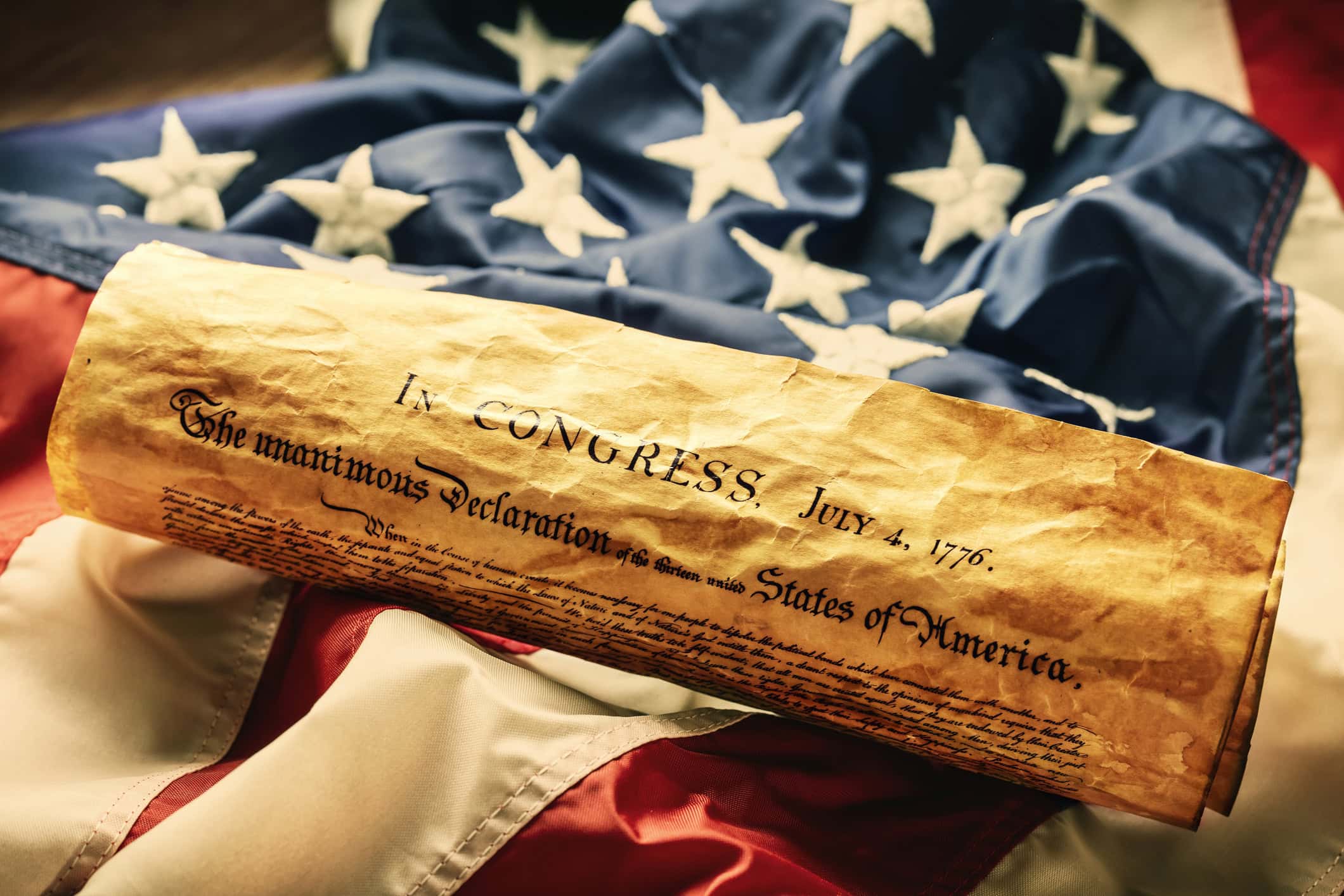 The Declaration of Independence of July 4, 1776, by which the Thirteen Colonies officially declared their separation from the British Crown and founded the United States of America, lies symbolically spread out on the American flag.