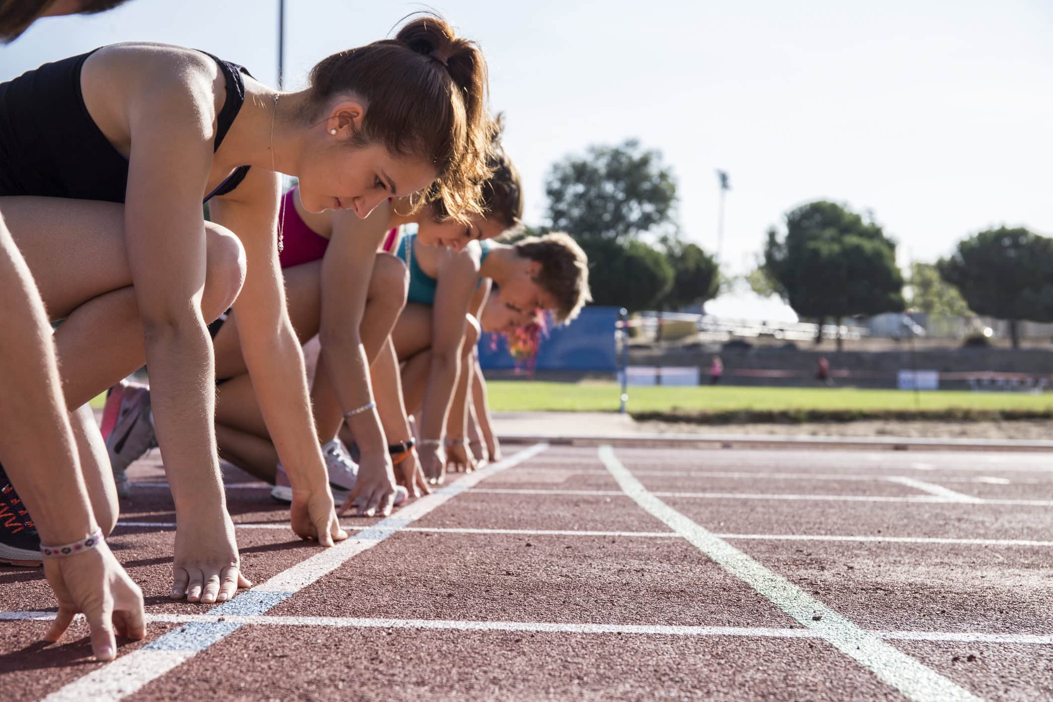 Female runners on tartan track in starting position