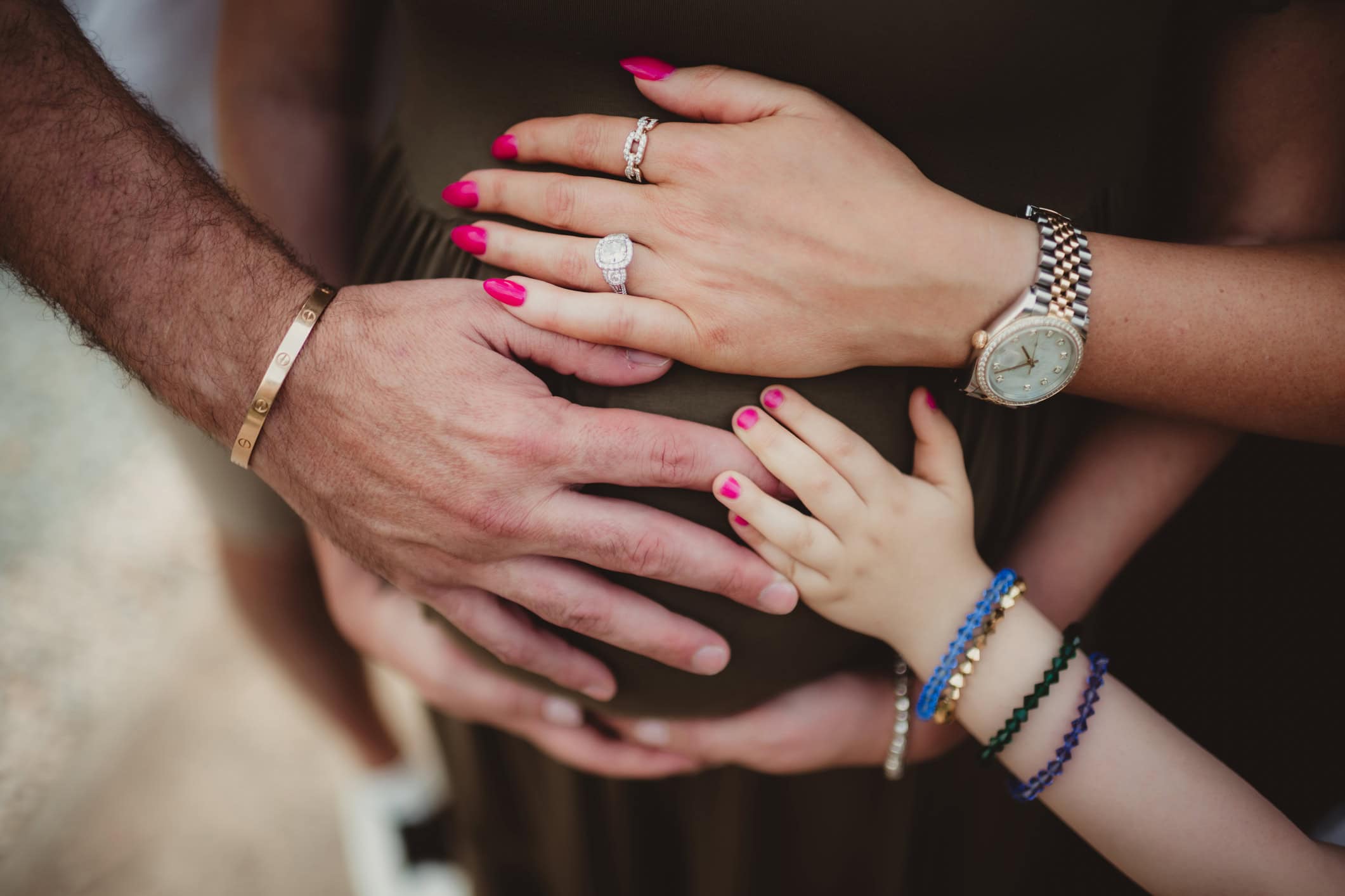 Mother, father and daughter with hands on pregnant belly